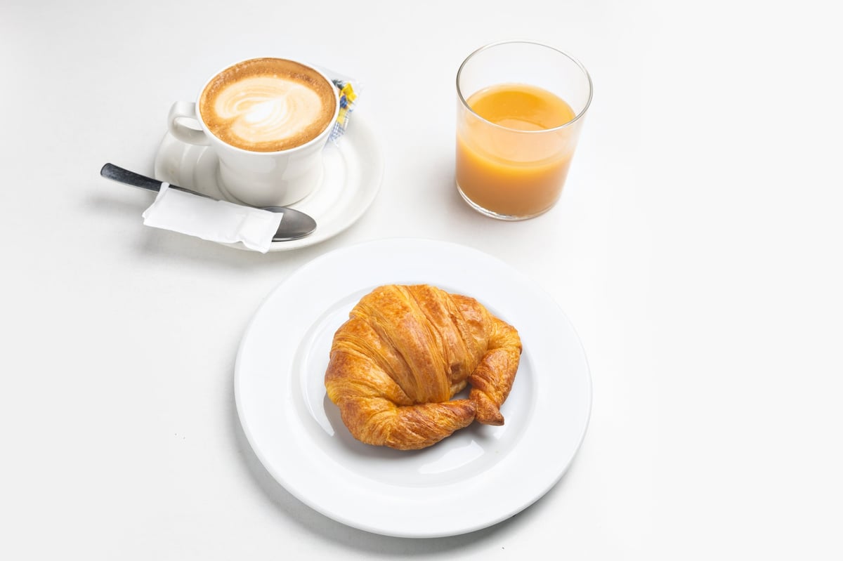 Capuchino y cruasán con luz de mañana